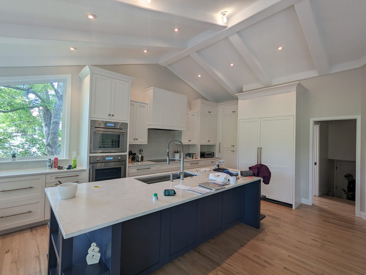 A bright white kitchen with refinished cabinetry and floating shelves